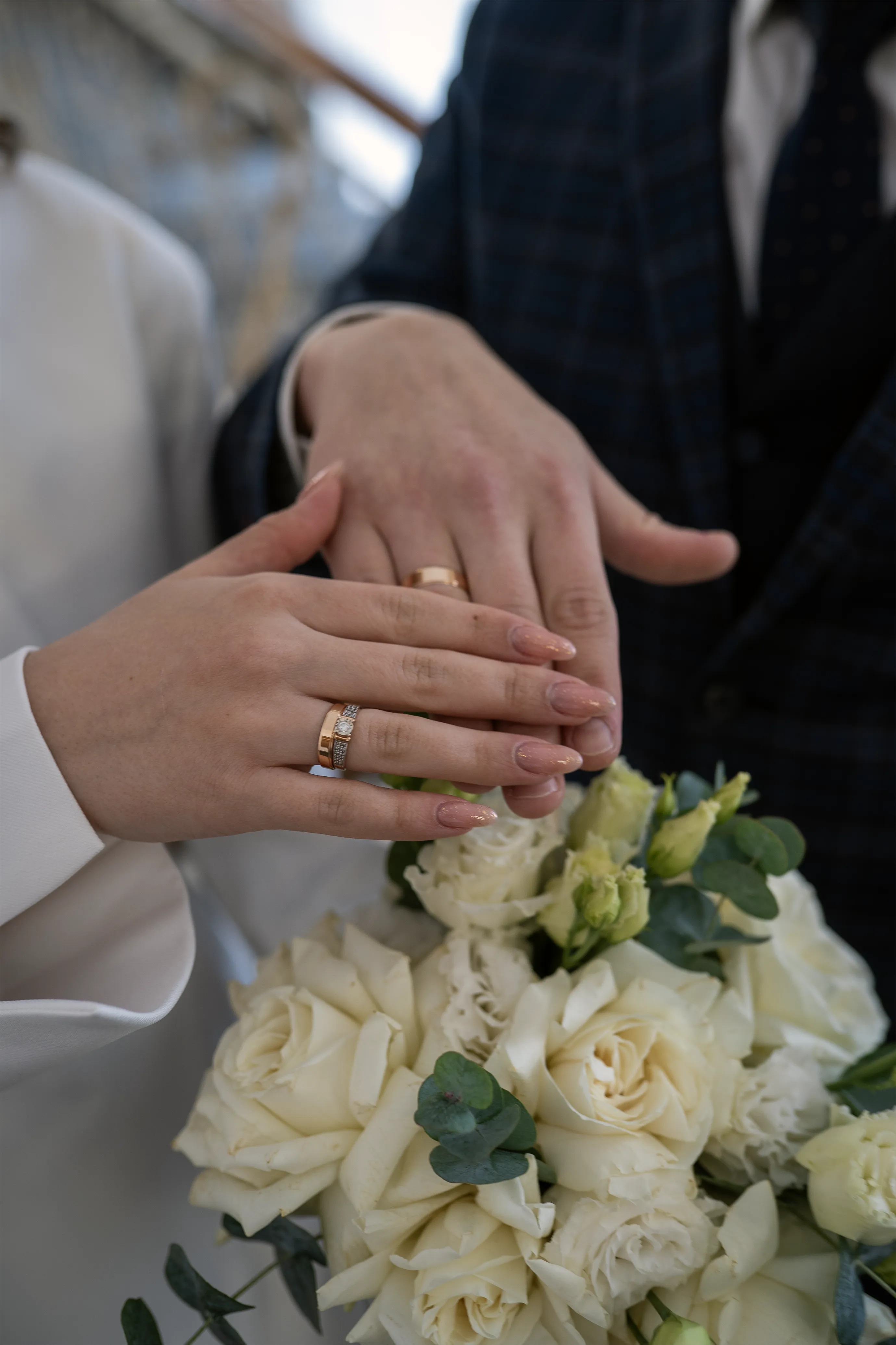 Руки с обручальными кольцами и свадебным букетом